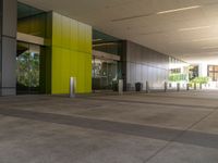 large yellow and green building near building entrance with plants and trees on either side of building