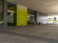 large yellow and green building near building entrance with plants and trees on either side of building