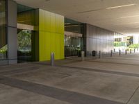 large yellow and green building near building entrance with plants and trees on either side of building