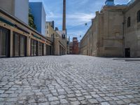 the sidewalk is paved with stones and has a bench in front of it, with no people inside