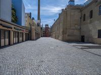 the sidewalk is paved with stones and has a bench in front of it, with no people inside