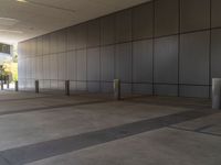 a concrete floor is surrounded by black walls and posts which are divided by lines of rectangulars