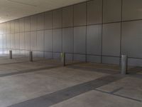 a concrete floor is surrounded by black walls and posts which are divided by lines of rectangulars