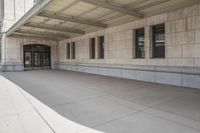 there are two empty windows in this building and the sidewalk has a cement floor with an empty area of cement
