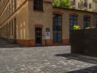 a sidewalk with chairs next to the brick building on the side, some have stairs and some buildings in the background