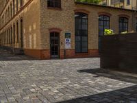 a sidewalk with chairs next to the brick building on the side, some have stairs and some buildings in the background