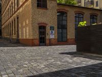 a sidewalk with chairs next to the brick building on the side, some have stairs and some buildings in the background