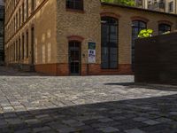 a sidewalk with chairs next to the brick building on the side, some have stairs and some buildings in the background