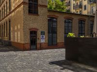 a sidewalk with chairs next to the brick building on the side, some have stairs and some buildings in the background