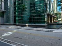 an empty road and two traffic lights at an intersection with tall buildings behind the building