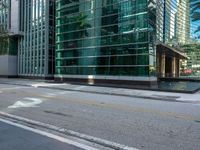 an empty road and two traffic lights at an intersection with tall buildings behind the building