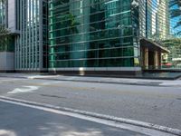 an empty road and two traffic lights at an intersection with tall buildings behind the building