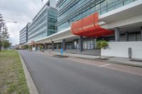 a paved city road with an empty parking space next to it and an office building in the background