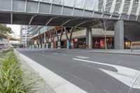 a large glass building with an overpass on the sidewalk and a bike parked on the sidewalk