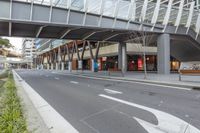 a large glass building with an overpass on the sidewalk and a bike parked on the sidewalk