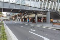 a large glass building with an overpass on the sidewalk and a bike parked on the sidewalk