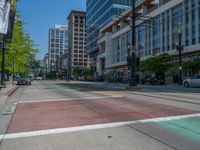 the green paint is painted on a bike path in front of an office building and large, trees