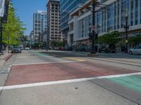 the green paint is painted on a bike path in front of an office building and large, trees