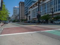 the green paint is painted on a bike path in front of an office building and large, trees