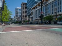 the green paint is painted on a bike path in front of an office building and large, trees