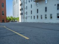 a street with a building near the building in the middle and on the left of which is a parking lot, as shown in this photo