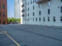 a street with a building near the building in the middle and on the left of which is a parking lot, as shown in this photo