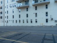 a street with a building near the building in the middle and on the left of which is a parking lot, as shown in this photo