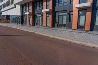 the empty red road is next to tall buildings on the side of the street and people walking outside