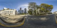 a circular lens image shows several buildings across the street from it, one on the road and another on the right