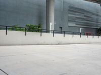 a skateboarder performs a trick on the sidewalk in front of a building and trees