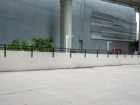 a skateboarder performs a trick on the sidewalk in front of a building and trees