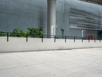 a skateboarder performs a trick on the sidewalk in front of a building and trees