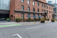 an empty city street with a bunch of plants on the curb and umbrellas on some buildings