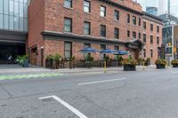 an empty city street with a bunch of plants on the curb and umbrellas on some buildings