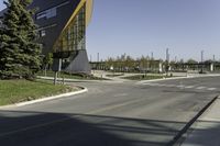 a traffic light on the street near a building and trees in the foreground of a paved city street