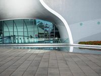 the outside side of a building with a pool and walkway, with a person standing on either side