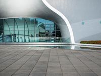 the outside side of a building with a pool and walkway, with a person standing on either side