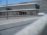 a gray building sitting next to an empty street on top of a sloped roof