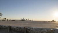 the large concrete bench is positioned on top of a cement wall with a city view in the distance