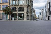 an empty street in front of some buildings on a rainy day with clouds in the sky