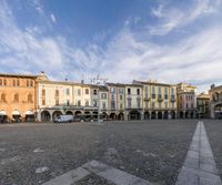 a square with several buildings, one in the center and an empty street near it