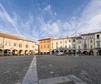 a square with several buildings, one in the center and an empty street near it