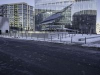 a group of glass office buildings on top of snow covered ground near street with paved road