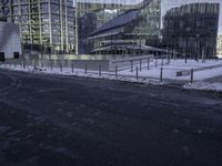 a group of glass office buildings on top of snow covered ground near street with paved road