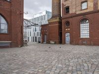 a brick patio that leads to an old building in an urban city setting with windows and some windows