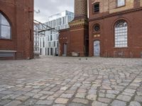 a brick patio that leads to an old building in an urban city setting with windows and some windows