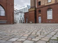 a brick patio that leads to an old building in an urban city setting with windows and some windows