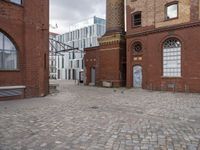 a brick patio that leads to an old building in an urban city setting with windows and some windows