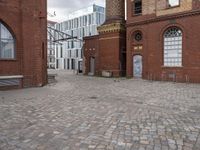 a brick patio that leads to an old building in an urban city setting with windows and some windows