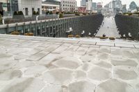 a paved walkway runs through a city with a big building in the background as well as large windows